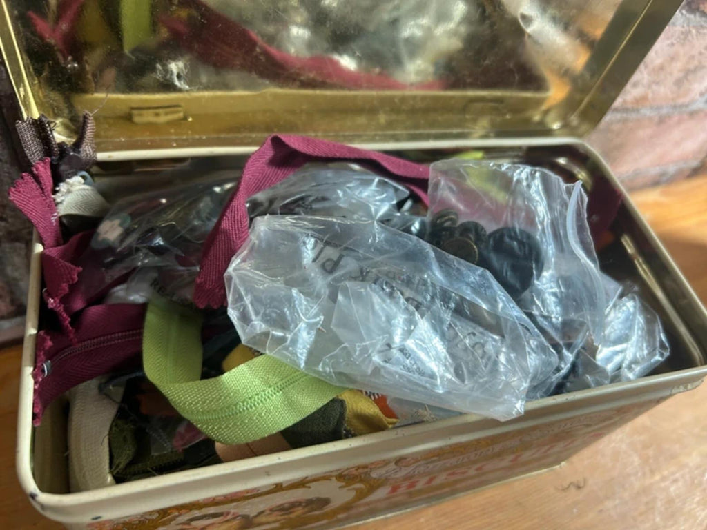 Bundle of zips and buttons in vintage tin
