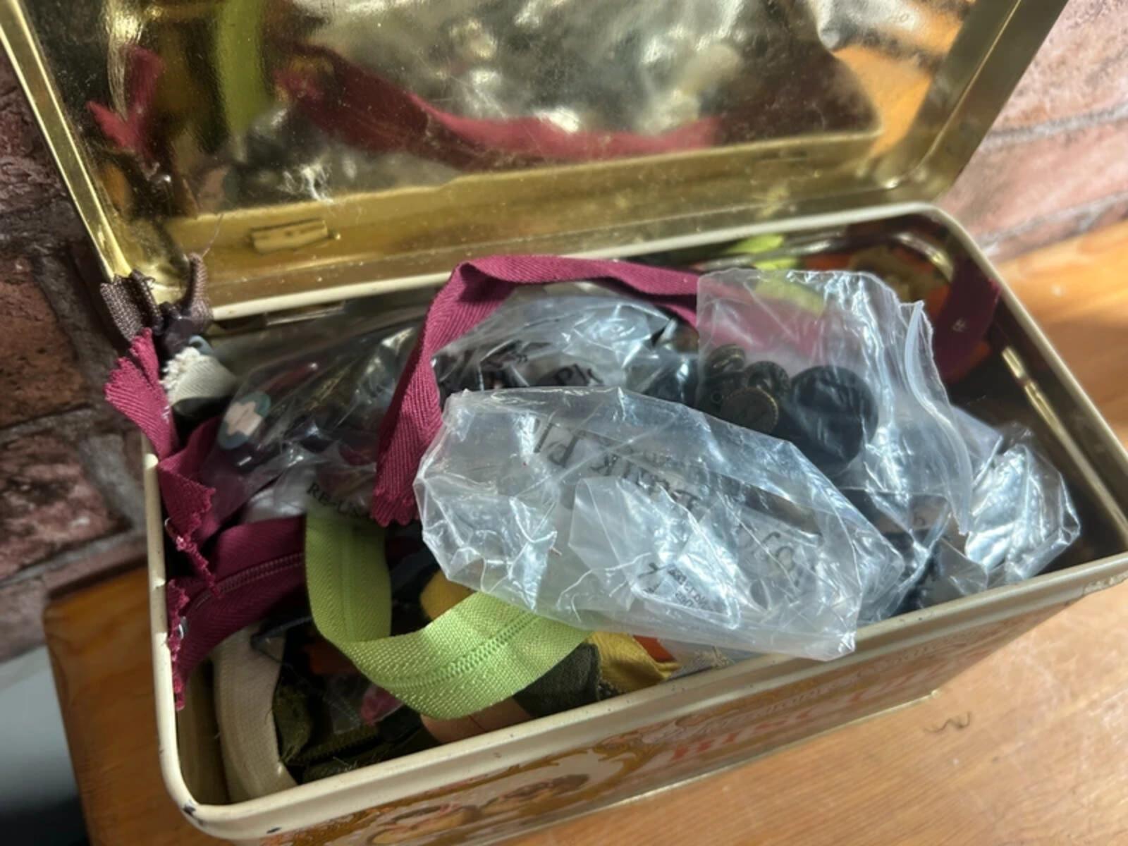 Bundle of zips and buttons in vintage tin