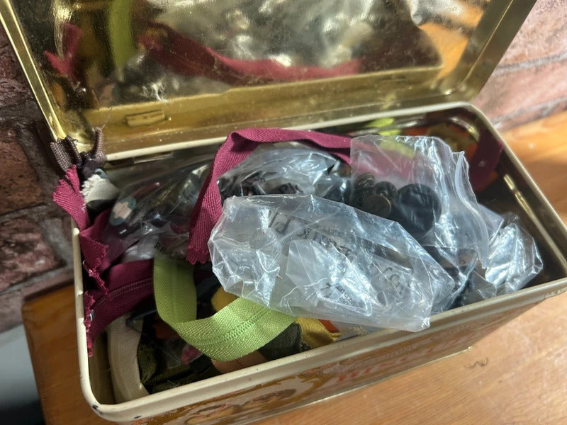 Bundle of zips and buttons in vintage tin